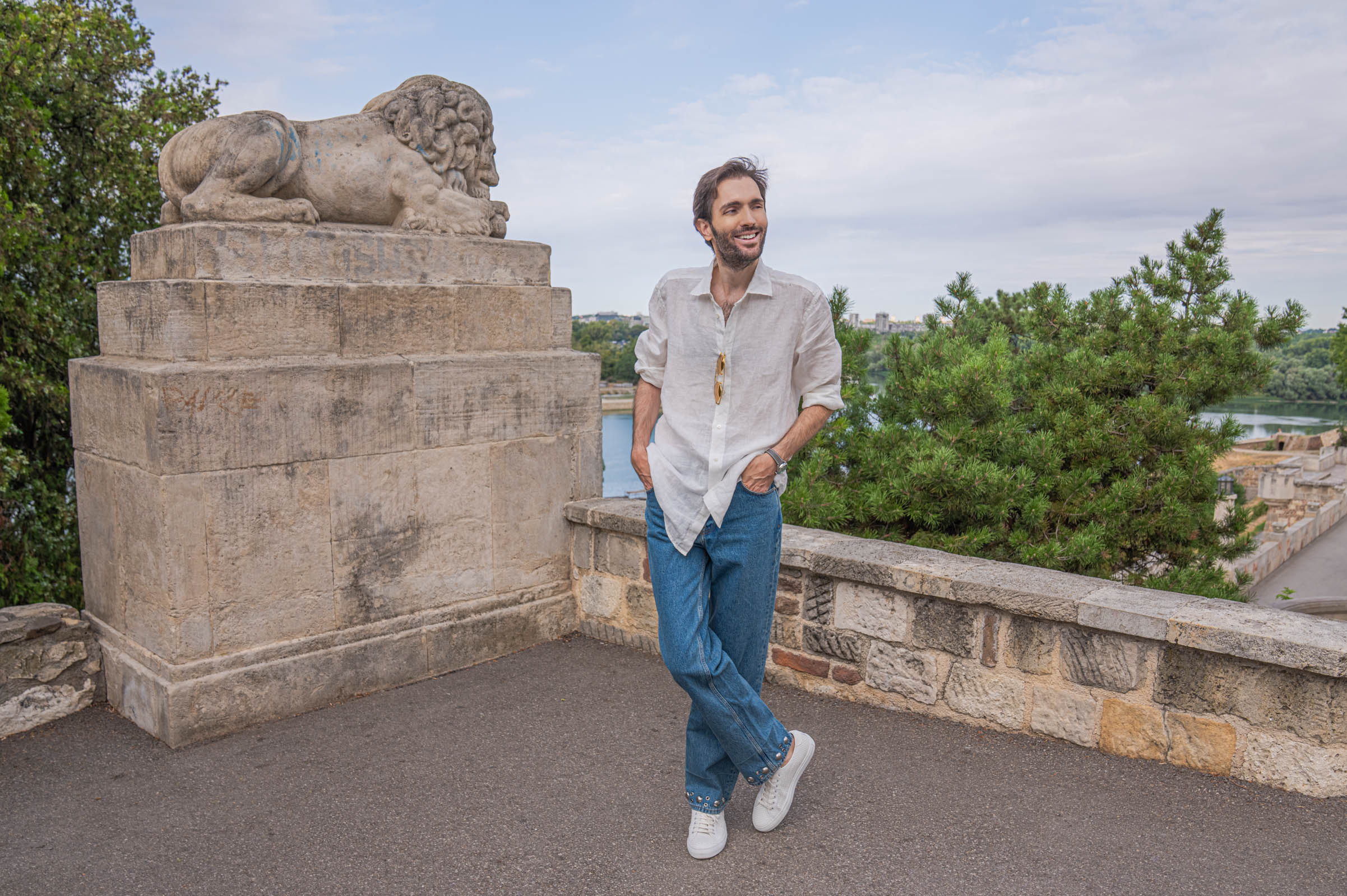 Wide view of Marko Tadić in a Valentino summer outfit under the Kalemegdan lion sculpture