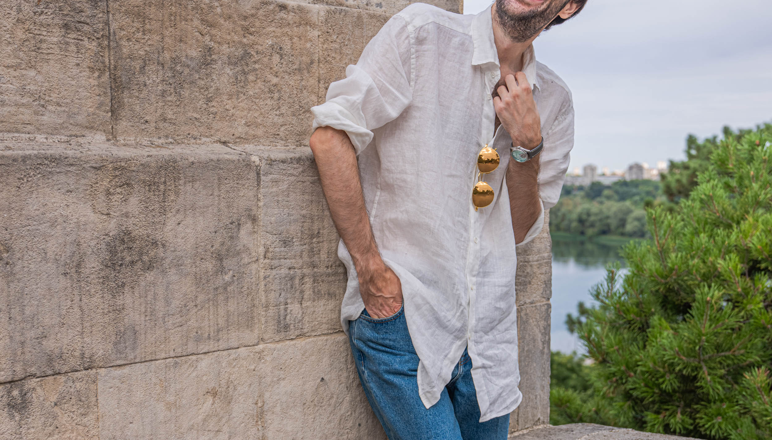 Marko Tadić leaning on limestone in a Valentino linen shirt with Linda Farrow aviators at the placket