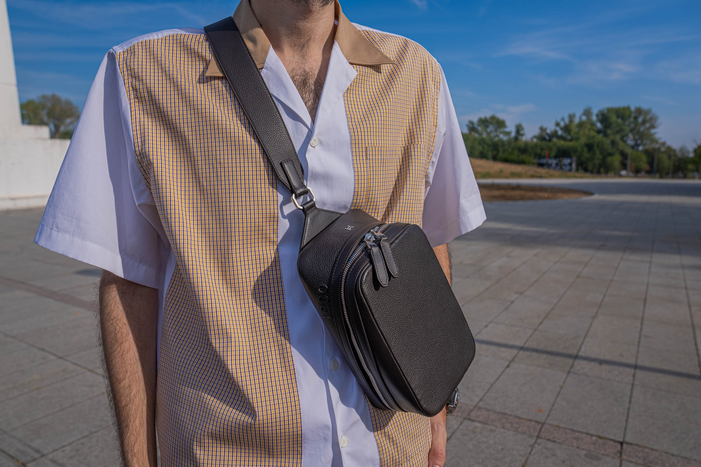 Close-up of Marko Tadić wearing the 1900 Tempo Grande Crossbody bag in grained leather over a Dsquared2 cotton poplin shirt with mustard check panels