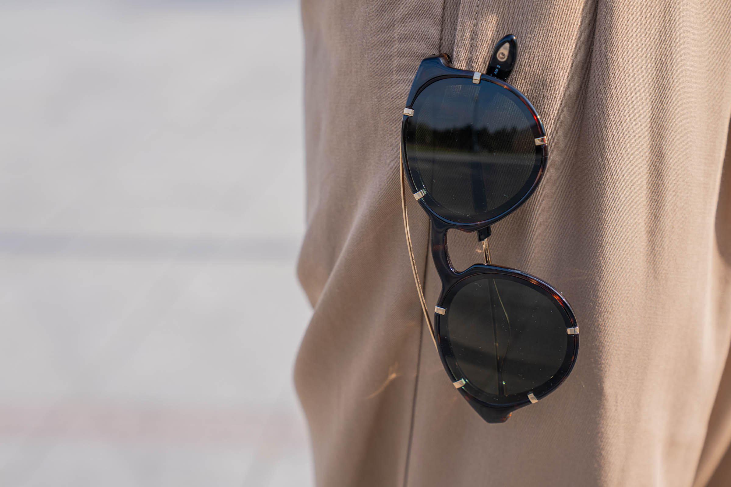 Givenchy dark tortoise round sunglasses with green lenses and gold-finish metal temples hooked onto the tan pleated Dsquared2 trousers of Marko Tadić