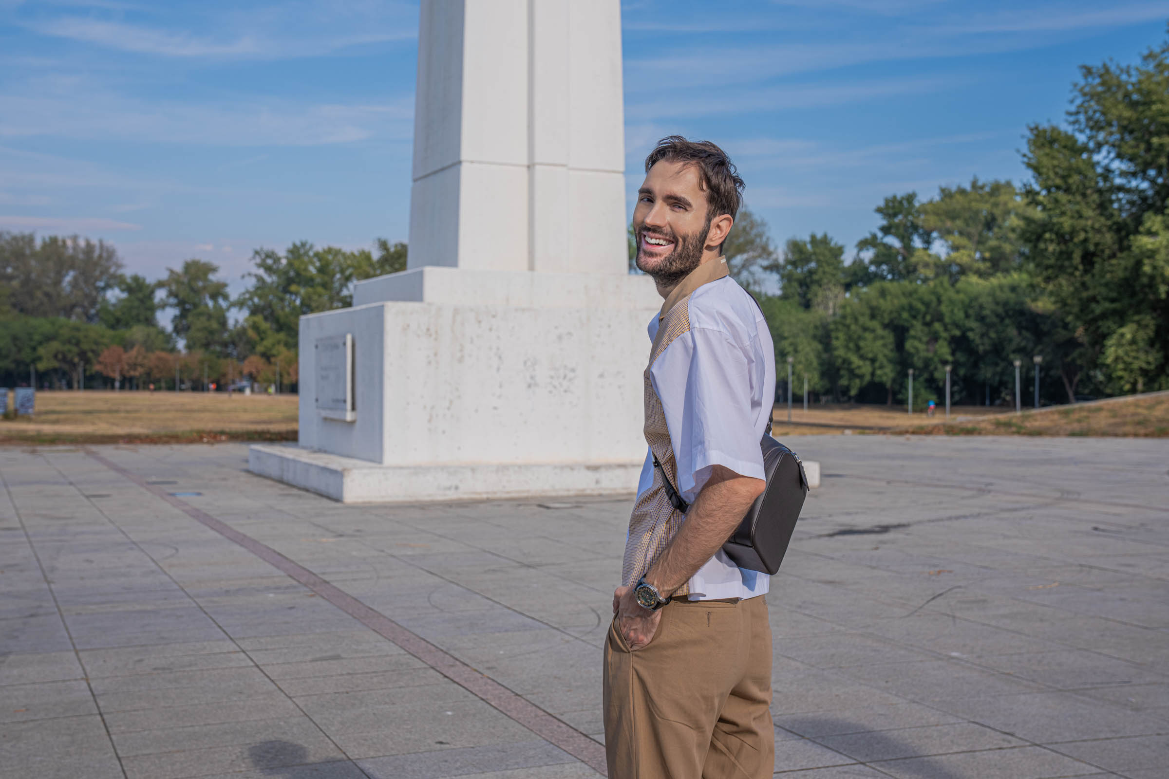 Marko Tadić looks back over his shoulder with a smile, the 1900 crossbody bag behind him and the white sleeves of his Dsquared2 outfit catching the sun