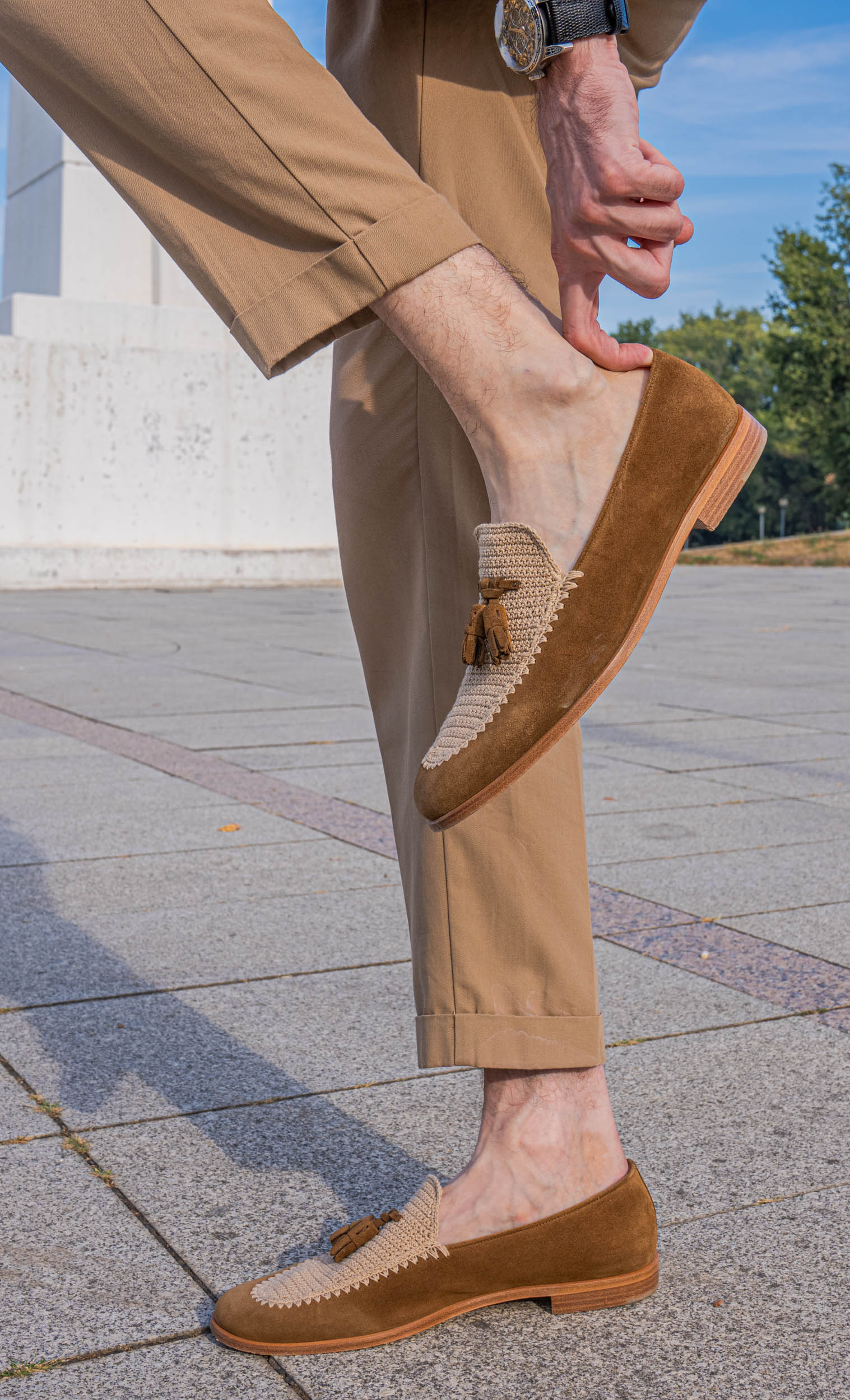 Marko Tadić lifts his foot to show the stacked heel and crochet panel of a Fratelli Rossetti Brera loafer, with the Bard's Whisper watch on his wrist