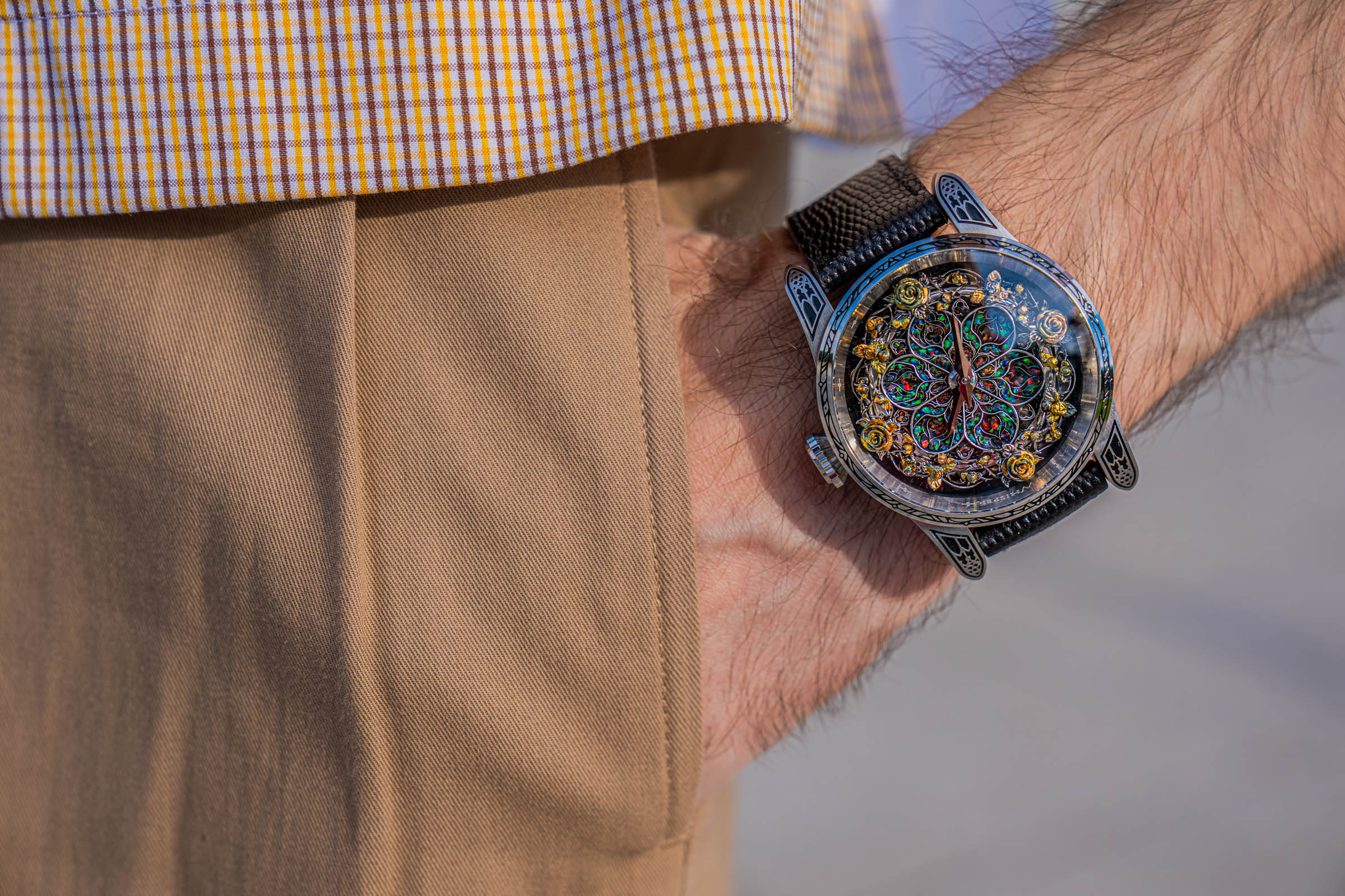 Bard's Whisper opal dial watch on the wrist of Marko Tadić as his hand rests in the pocket of pleated tan Dsquared2 trousers below a check shirt hem
