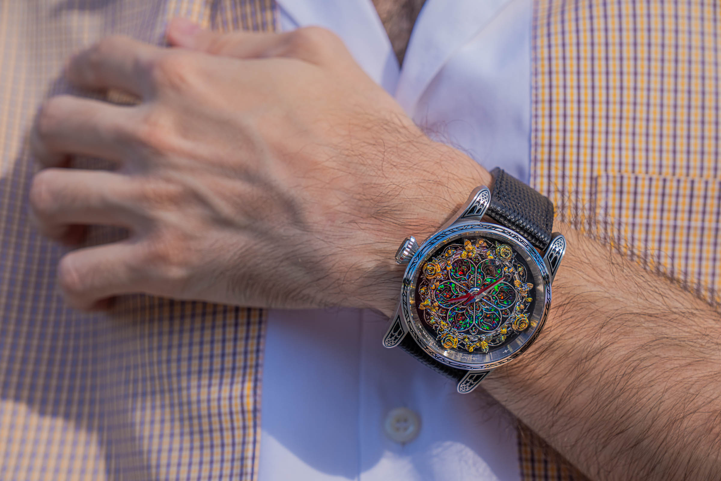 Top-down view of the Bard's Whisper watch on Marko Tadić's wrist, showing its sterling silver rose window, opal inlay and rose wreath over a Dsquared2 shirt