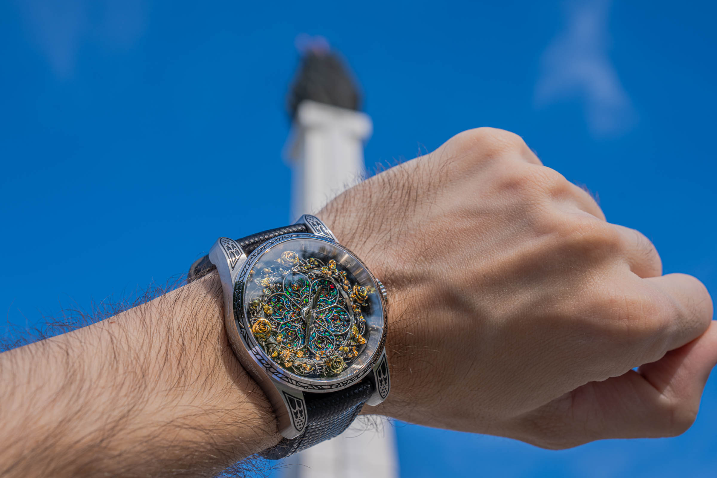 Low-angle shot of the Bard's Whisper Divine Comedy watch against a deep blue sky, worn by Mr.M blog founder Marko Tadić, with opal dial and polished steel case
