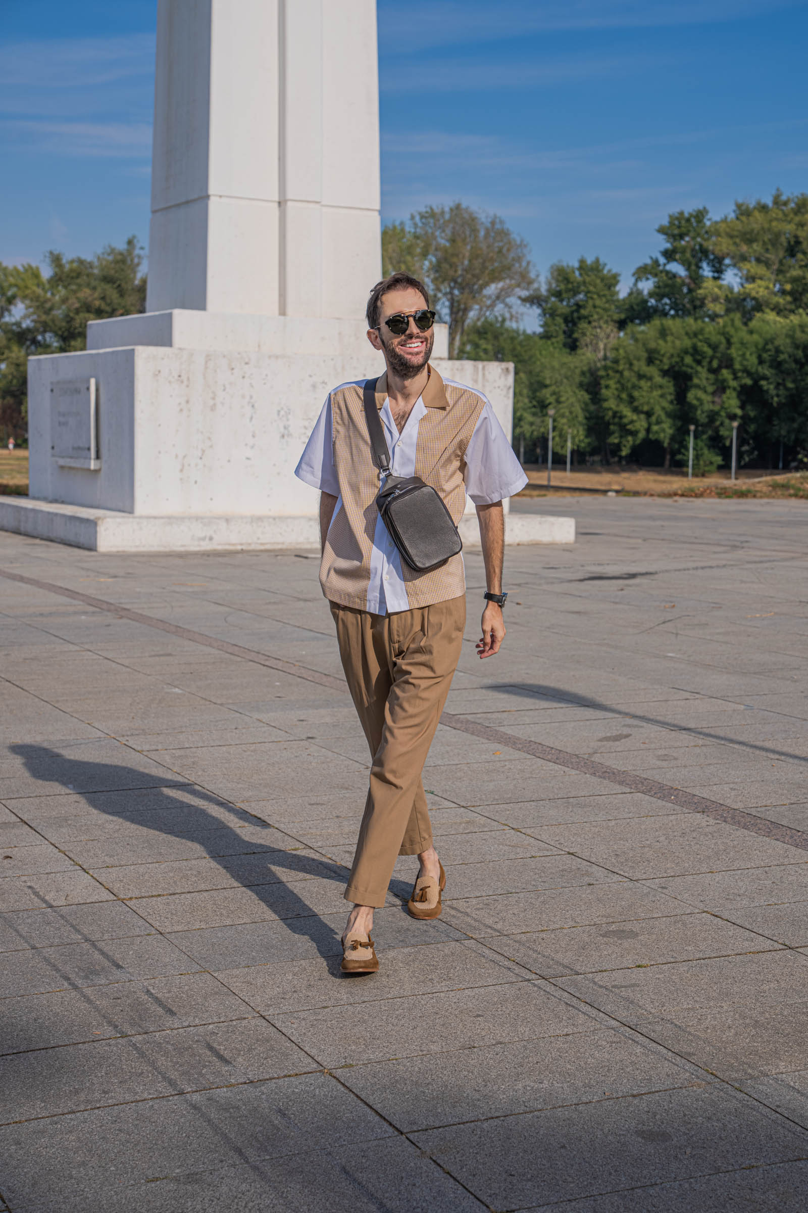 Mid-stride shot of Mr.M founder Marko Tadić showing how Dsquared2 pleated trousers move, paired with a grained leather 1900 bag and Givenchy round sunglasses