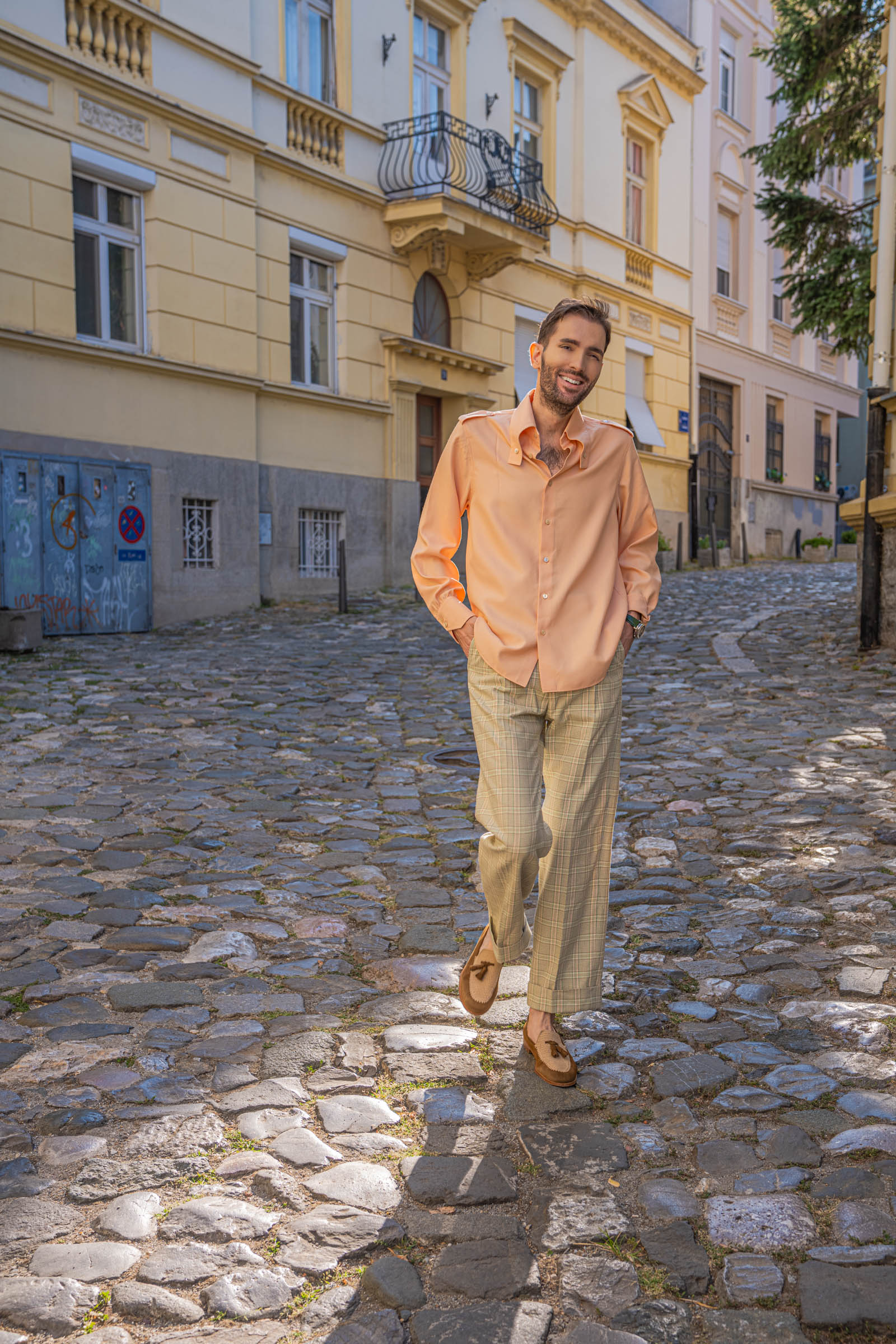 Marko Tadić strolls with hands in pockets in a relaxed peach silk shirt and wide Gucci check trousers