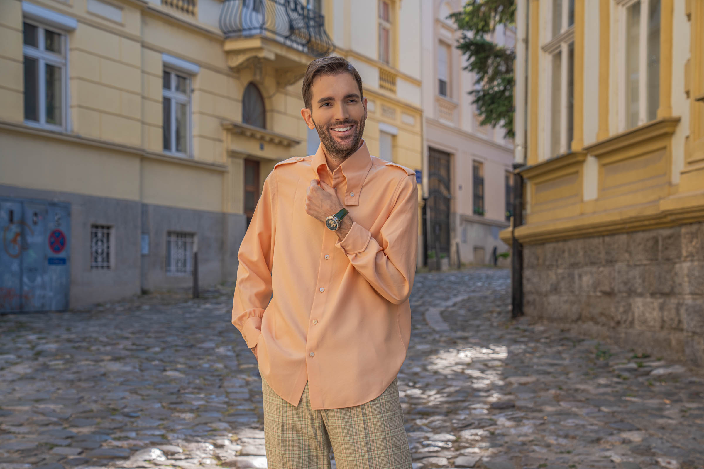 Smiling Marko Tadić adjusts the collar of his peach Gucci silk shirt, the Dmitry Chugunov watch on his wrist