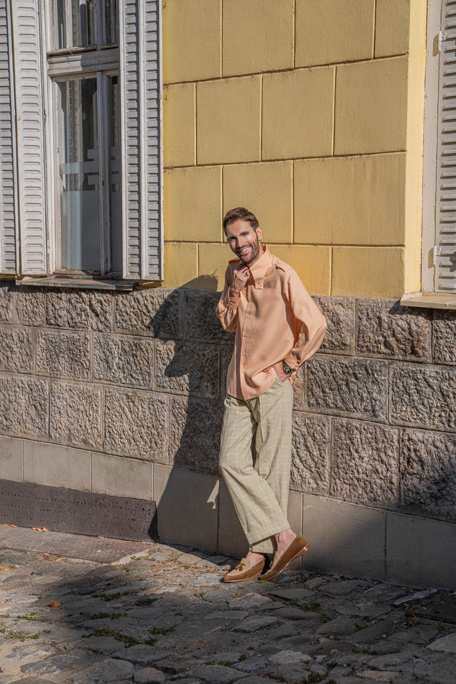 Marko Tadić, founder of Mr.M, leans on a yellow stone wall in a Dolce Vita look by Gucci and Fratelli Rossetti