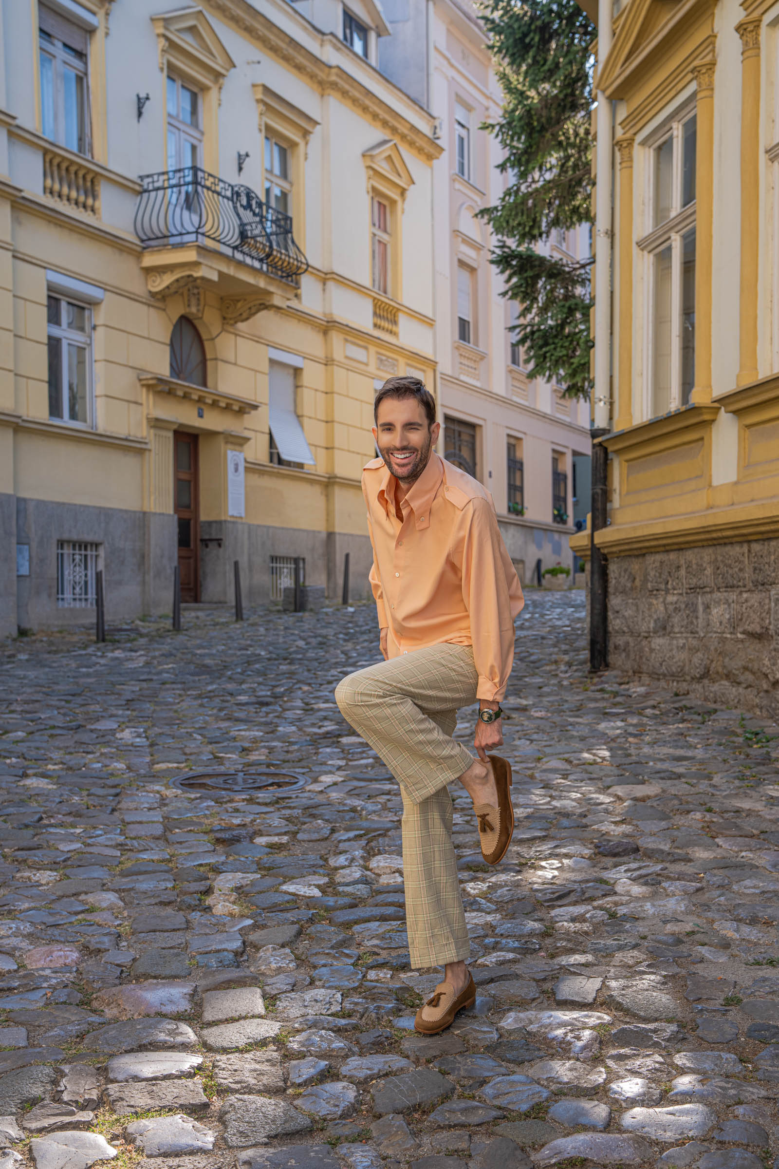 Marko Tadić lifts one knee to show the sole of his Fratelli Rossetti Brera loafer below cuffed Gucci trousers