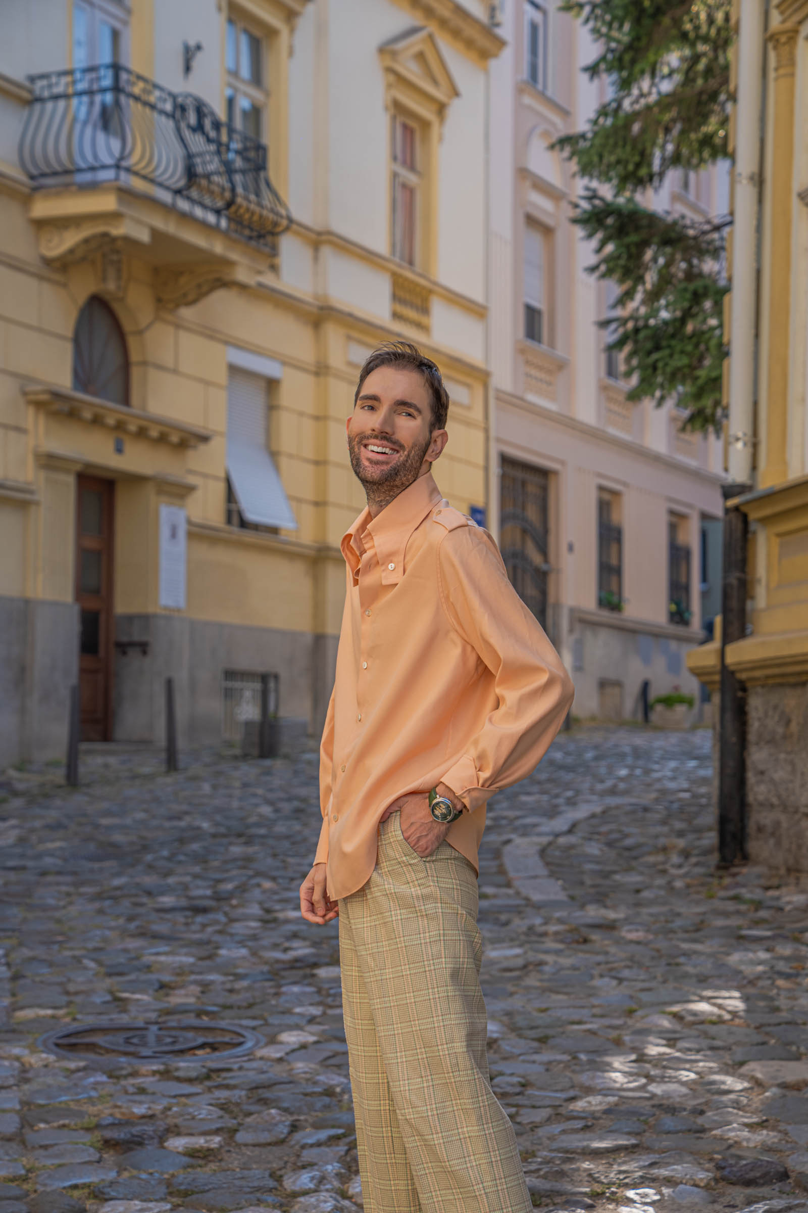 Marko Tadić smiles over his shoulder in a peach silk shirt and Gucci Heritage Light Green check trousers
