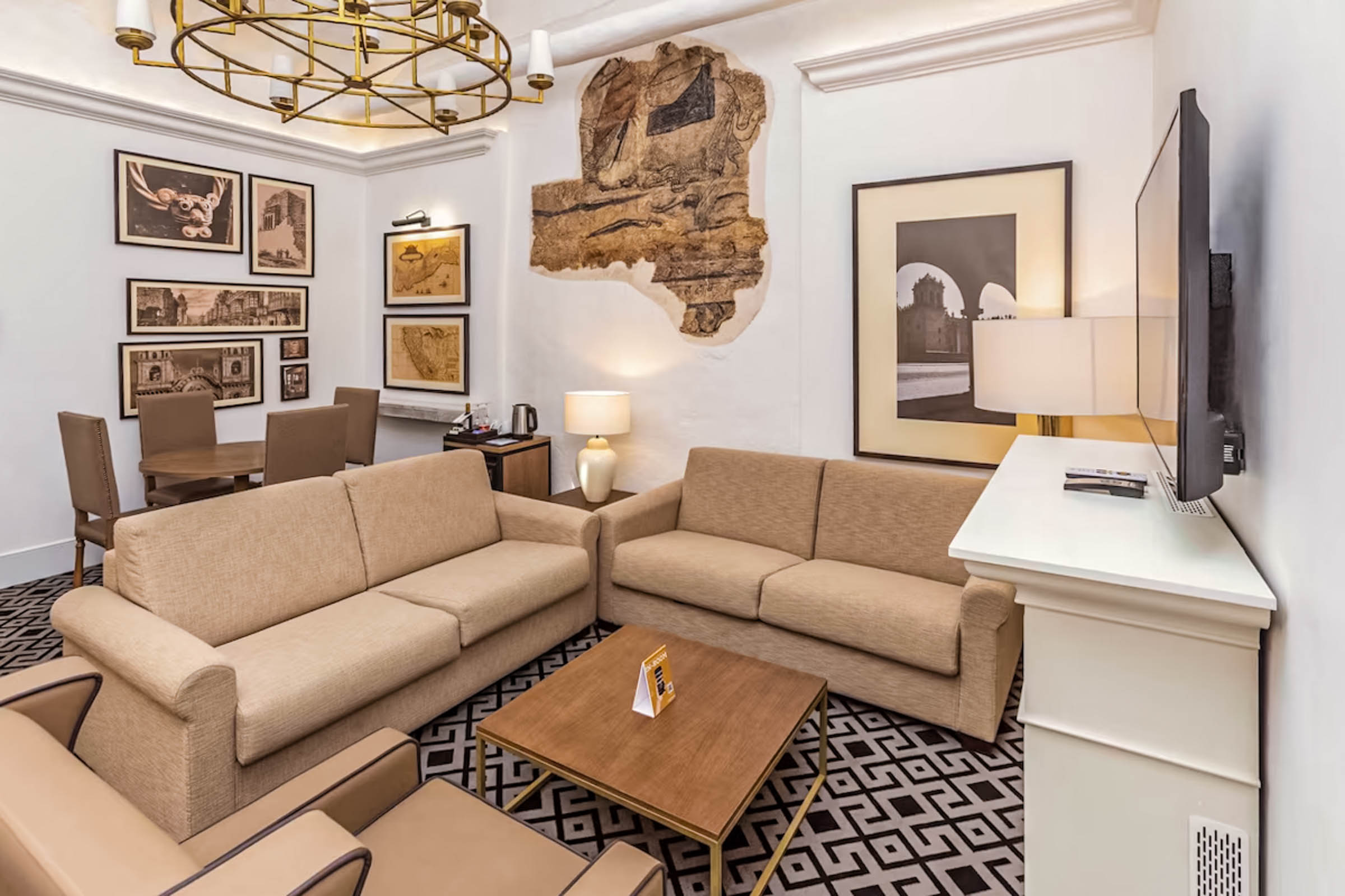 Dnevni boravak luksuzne Imperial Suite sobe u hotelu Casa Andina Premium Cusco, sa udobnim bež sofama, drvenim stočićem i ukusnim detaljima.