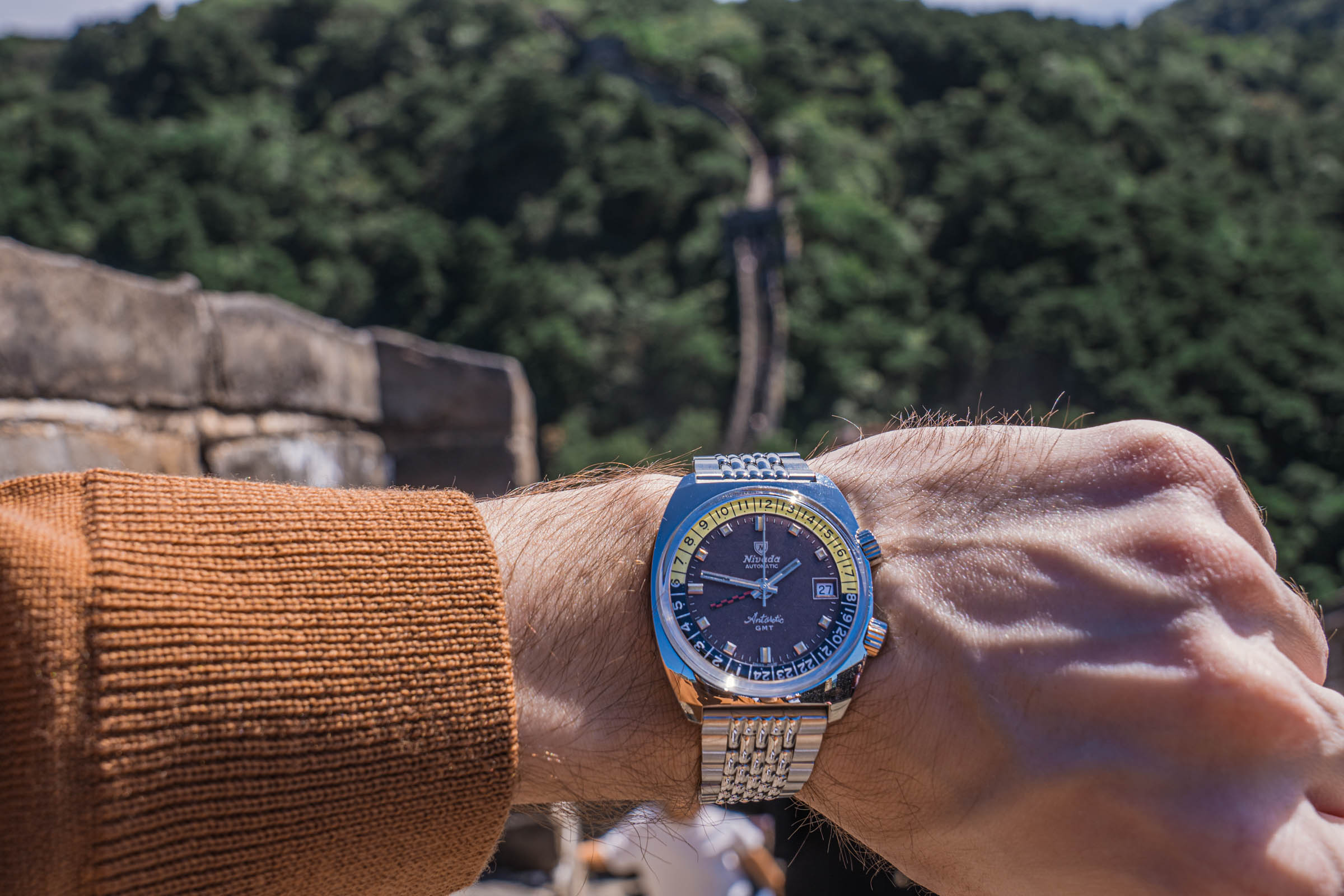 Švajcarski Nivada Grenchen Antarctic GMT sat koji je putovao na Antarktik, nošen u outfitu sa ALPHA STUDIO rolkom na Kineskom zidu