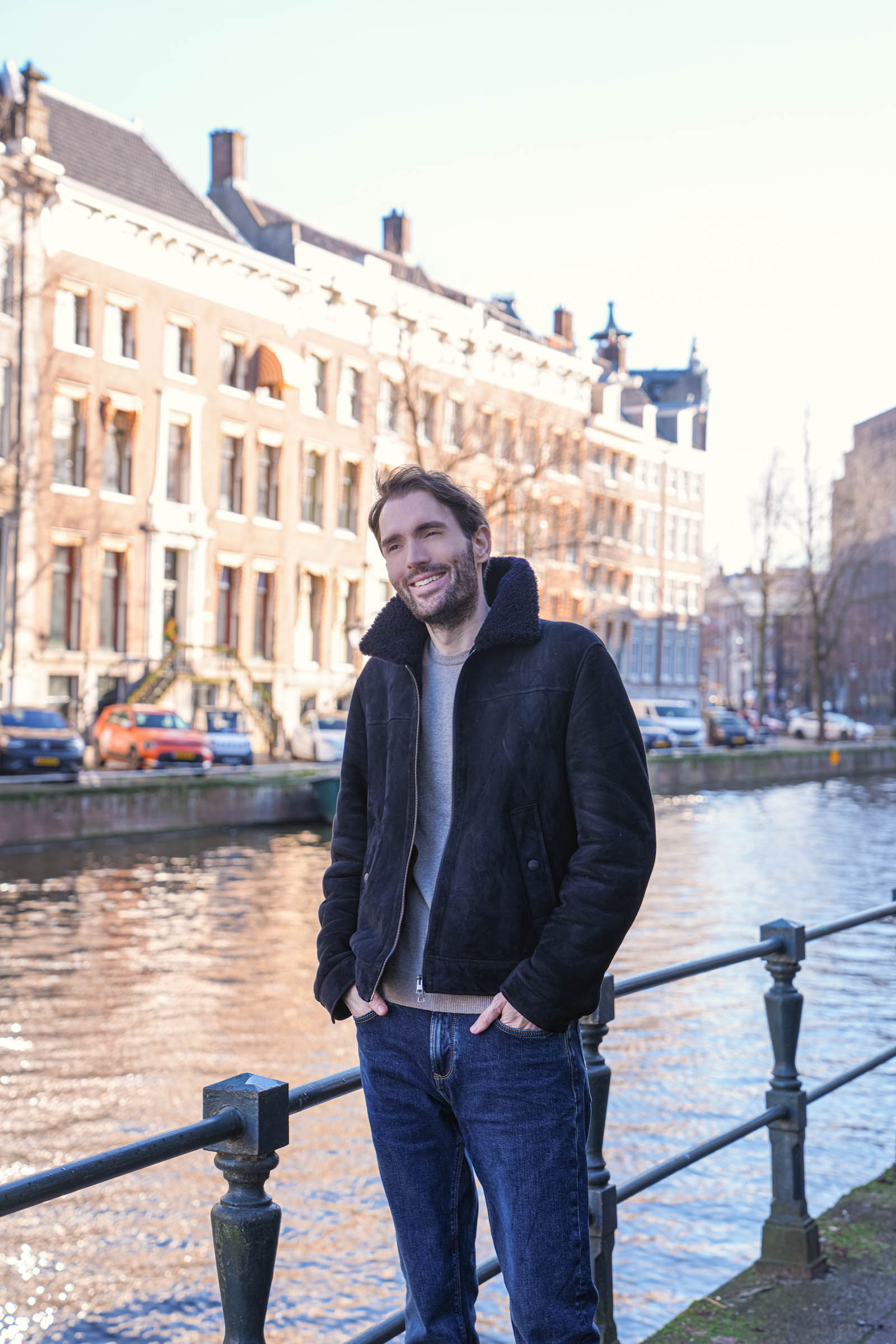 Mr.M by Marko Tadić bloger Marko Tadić sa osmehom pored amsterdamskog kanala u Façonnable bombarder jakni sa krznom – zimski muški stil inspirisan francuskom elegancijom i holandskom arhitekturom.